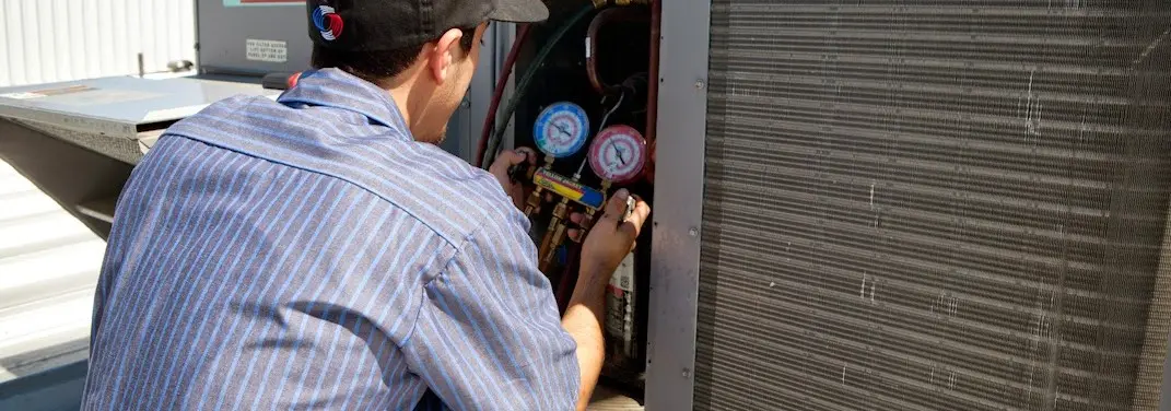 HVAC technician servicing a condenser unit in Pacific